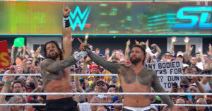 Roman Reigns and Jey Uso celebrating victory at WWE SummerSlam in front of cheering crowd