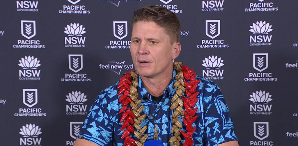 Gardiner Toa Samoa coach at 2025 Pacific Championships press conference in blue shirt with red lei against NSW Government backdrop
