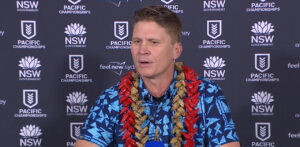 Gardiner Toa Samoa coach at 2025 Pacific Championships press conference in blue shirt with red lei against NSW Government backdrop