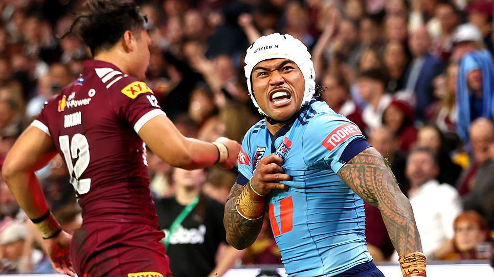 NSW Blues player Brian To'o celebrating intensely in front of QLD Maroons player Jeremiah Nanai during a State of Origin rugby league match.