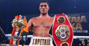 Jai Opetaia standing in a boxing ring holding the IBF and The Ring cruiserweight world title belts.