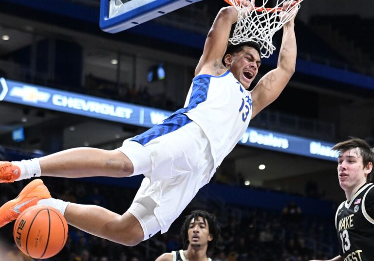 Roman Siulepa performing a powerful one-handed dunk during a high-stakes basketball game against Wake Forest.