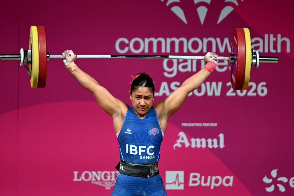 Samoan weightlifter successfully lifts a heavy barbell overhead during competition at the 2026 Commonwealth Games in Glasgow, representing Team Samoa in Olympic weightlifting.